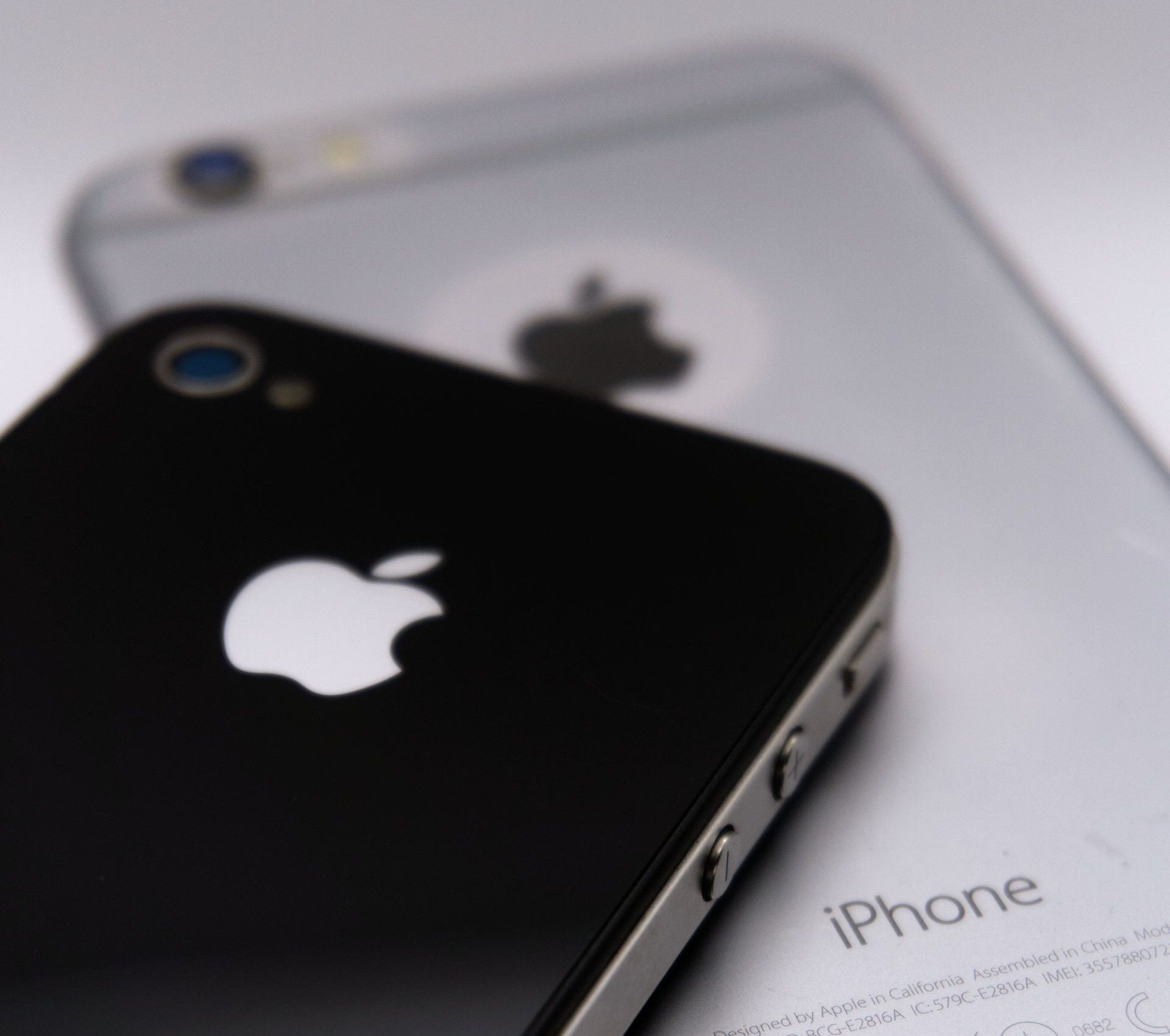 Detailed shot of two smartphones featuring the Apple logo, showcasing modern technology design.