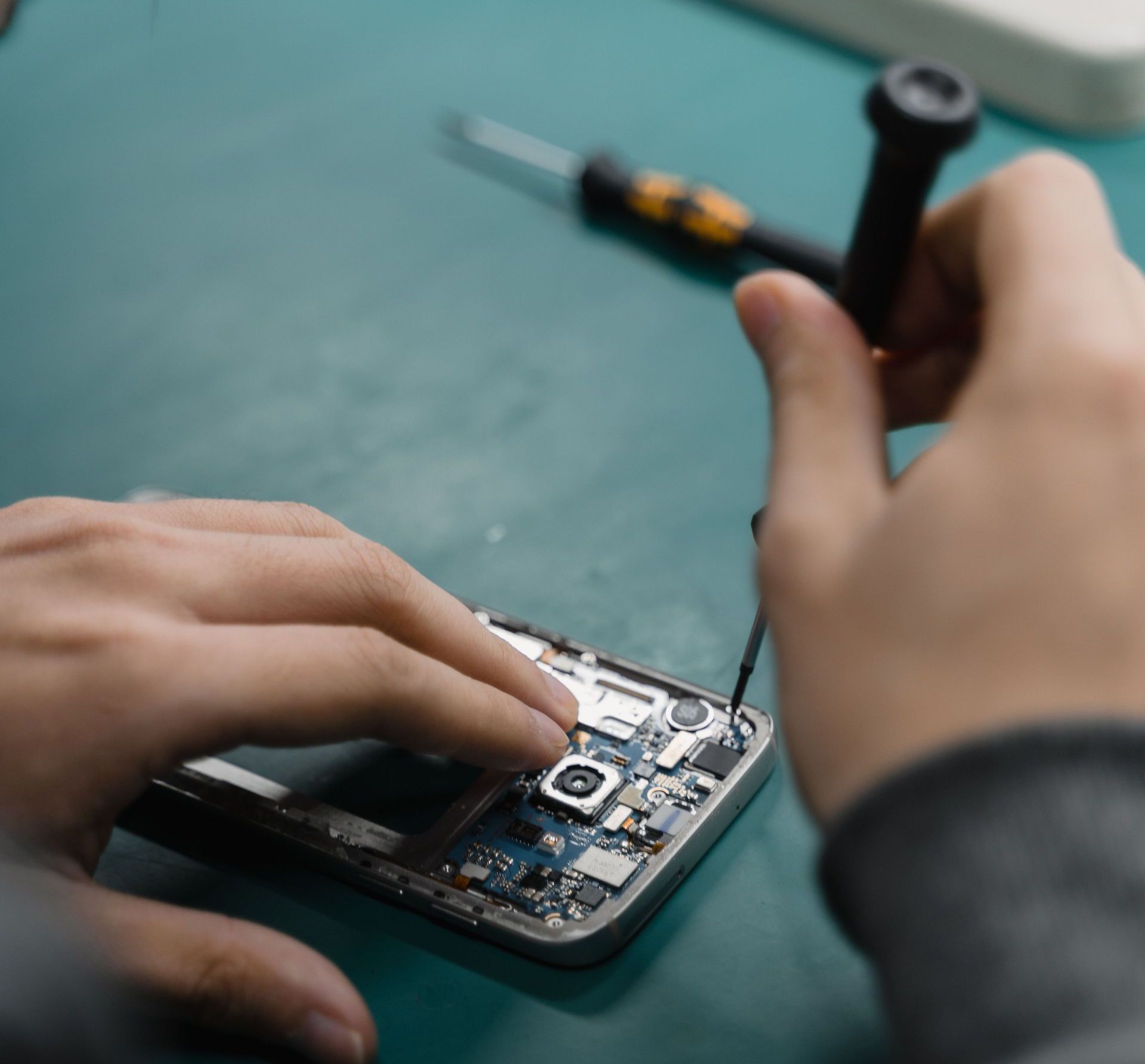 A focused view of repairing a smartphone circuit board with tools by hand.