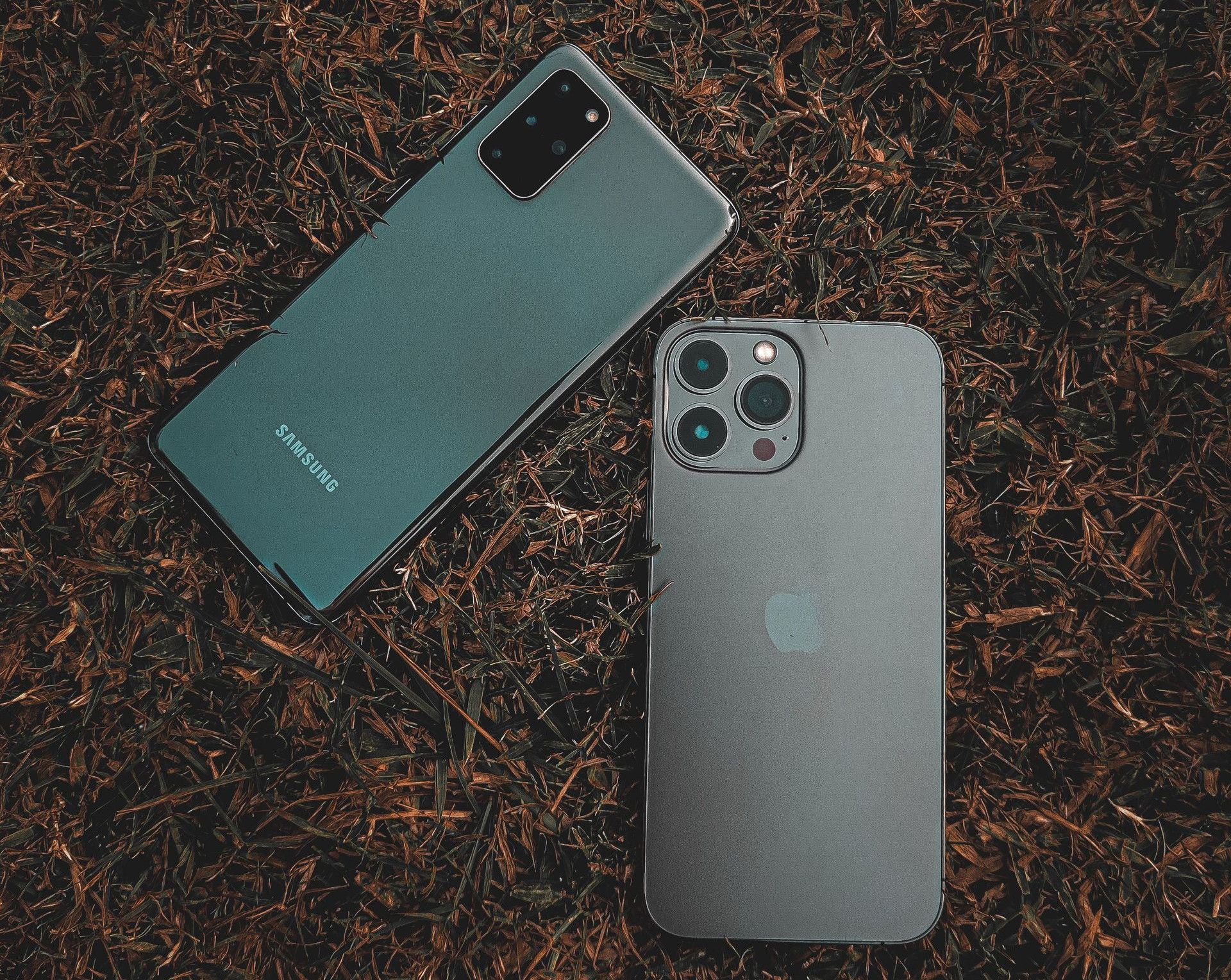 Top view of Samsung and iPhone placed on a grassy surface, showcasing modern smartphone design.